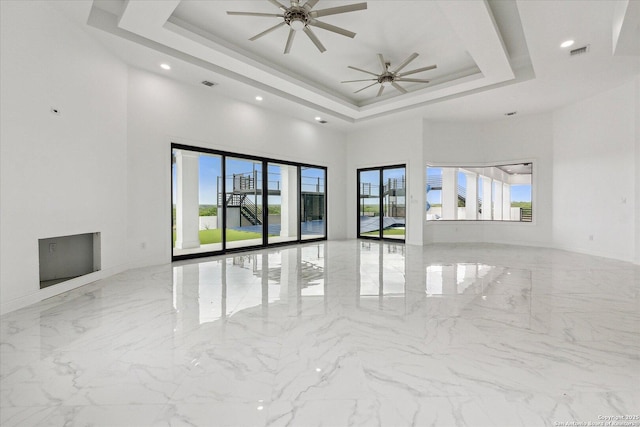 unfurnished room featuring a high ceiling, visible vents, a wealth of natural light, and a tray ceiling