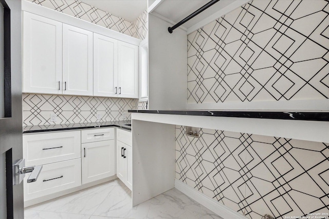 kitchen featuring marble finish floor, backsplash, white cabinets, and dark countertops