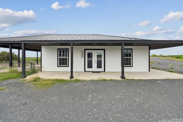 view of front of house featuring metal roof, stucco siding, french doors, and a standing seam roof