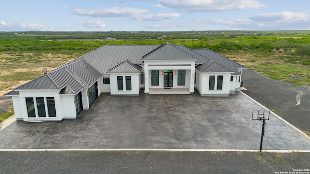 rear view of house with an attached garage, metal roof, driveway, and a standing seam roof