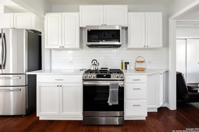 kitchen with white cabinetry, decorative backsplash, appliances with stainless steel finishes, light countertops, and dark wood-style flooring