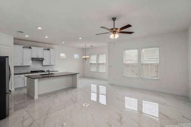 kitchen featuring recessed lighting, a sink, marble finish floor, freestanding refrigerator, and ceiling fan with notable chandelier