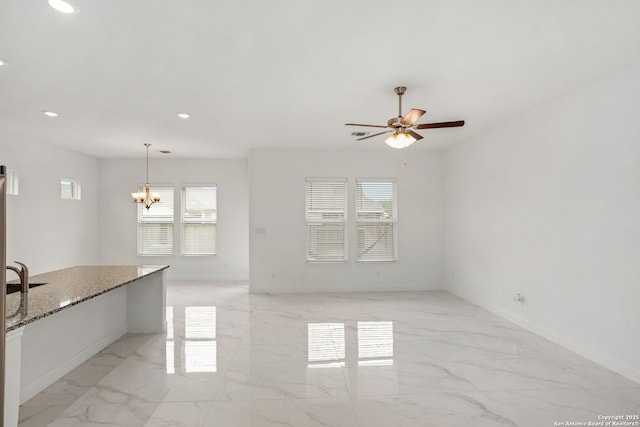unfurnished living room featuring recessed lighting, marble finish floor, baseboards, and ceiling fan with notable chandelier
