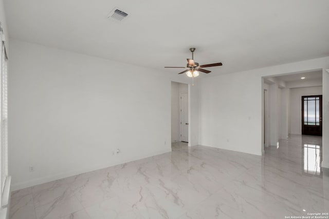 spare room featuring a ceiling fan, visible vents, marble finish floor, and baseboards