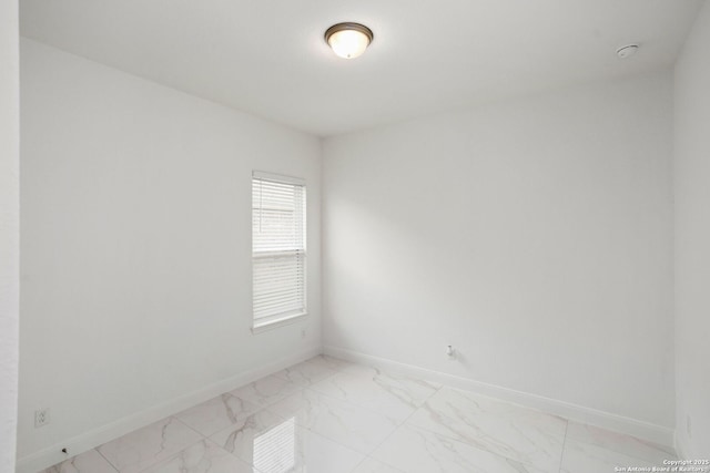unfurnished room featuring marble finish floor and baseboards