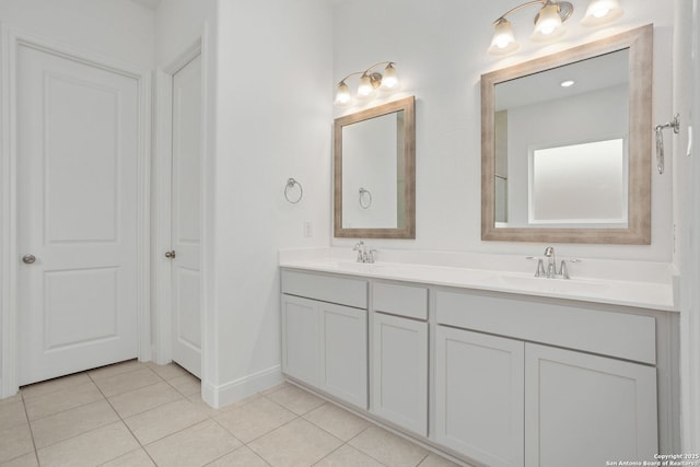 full bath featuring tile patterned floors, baseboards, double vanity, and a sink