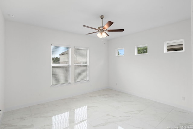 empty room featuring a ceiling fan, marble finish floor, and baseboards