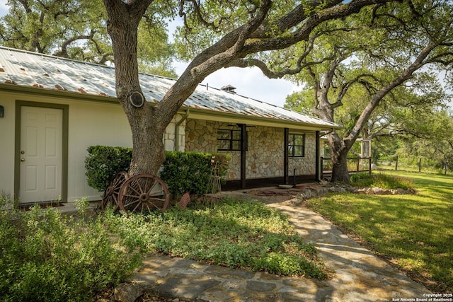 view of front of house featuring a standing seam roof, metal roof, and stone siding