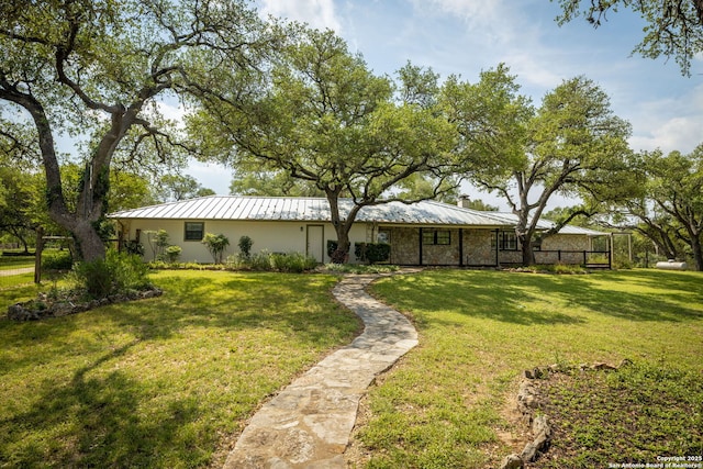 rear view of property with a standing seam roof, metal roof, and a yard