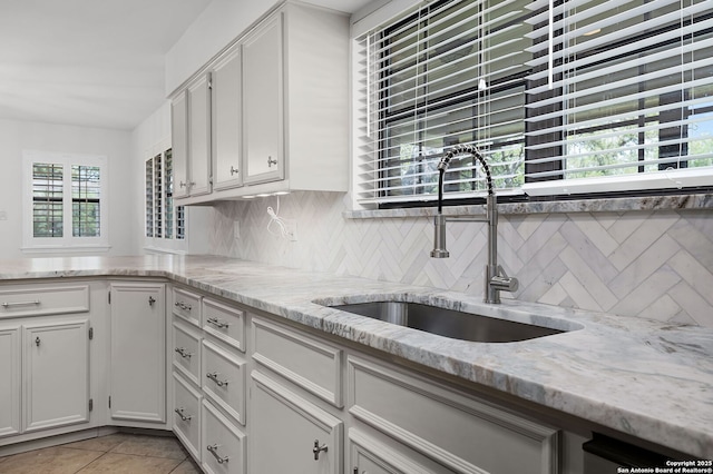 kitchen with white cabinetry, tasteful backsplash, light tile patterned floors, and a sink