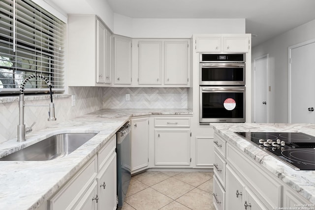 kitchen with decorative backsplash, light tile patterned floors, appliances with stainless steel finishes, white cabinets, and a sink