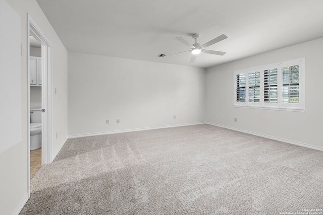 carpeted spare room featuring ceiling fan and baseboards