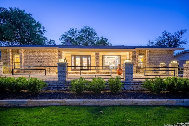 view of front of home featuring a chimney, brick siding, and french doors