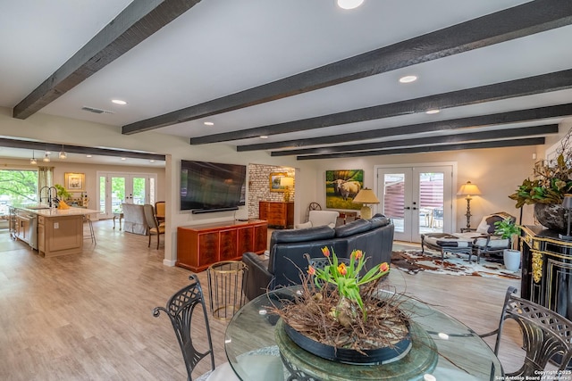 dining space with beamed ceiling, light wood finished floors, visible vents, and french doors