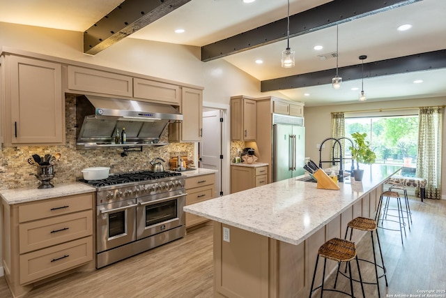 kitchen featuring a sink, premium appliances, under cabinet range hood, lofted ceiling with beams, and light wood-type flooring