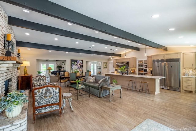 living area featuring recessed lighting, lofted ceiling with beams, a fireplace, and light wood-style flooring