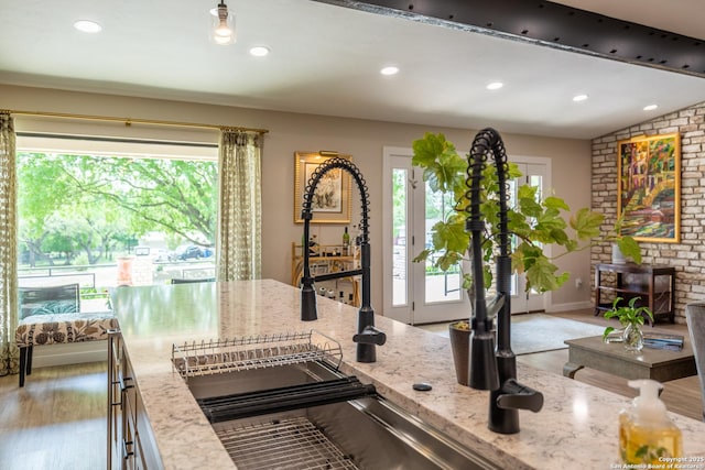 kitchen featuring light stone counters, recessed lighting, and a sink