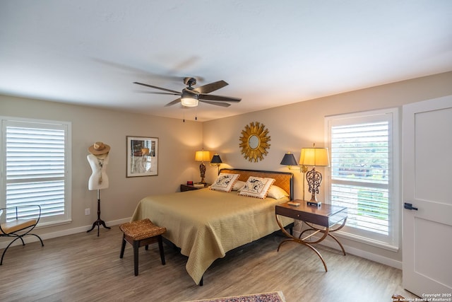 bedroom with multiple windows, wood finished floors, and baseboards