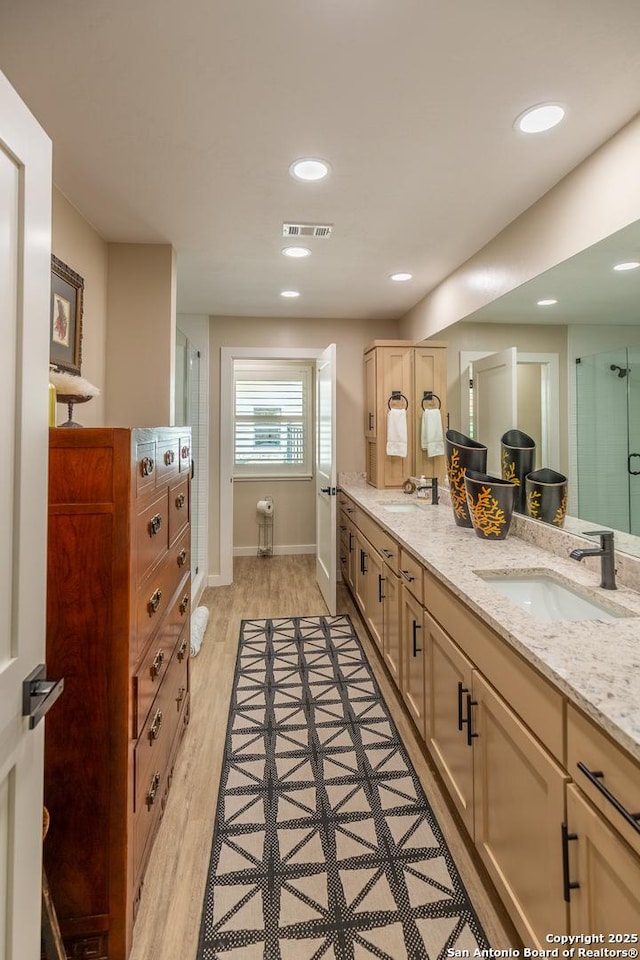full bath with wood finished floors, visible vents, a stall shower, and a sink