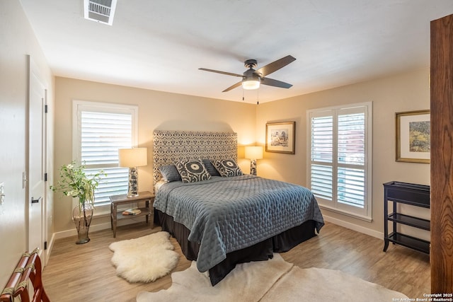 bedroom featuring baseboards, visible vents, wood finished floors, and ceiling fan