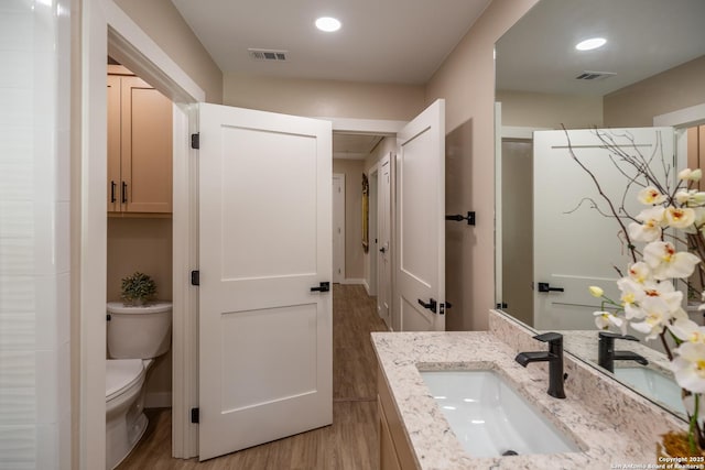 full bathroom featuring visible vents, wood finished floors, toilet, and vanity