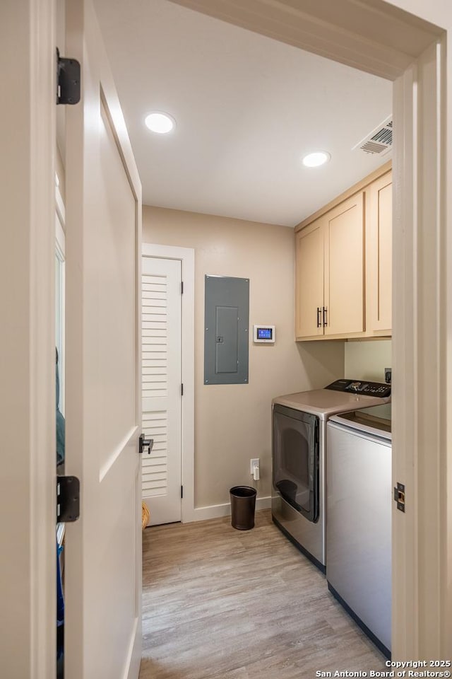 washroom featuring independent washer and dryer, visible vents, electric panel, baseboards, and cabinet space