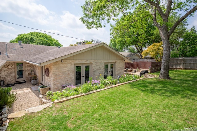 back of house with a shingled roof, fence, a yard, french doors, and brick siding