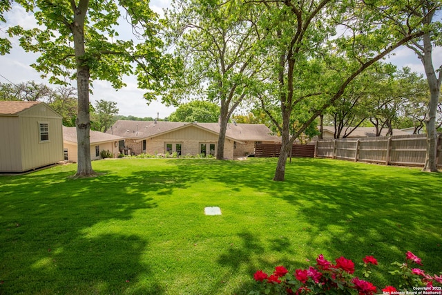 view of yard featuring an outbuilding, a storage unit, and fence