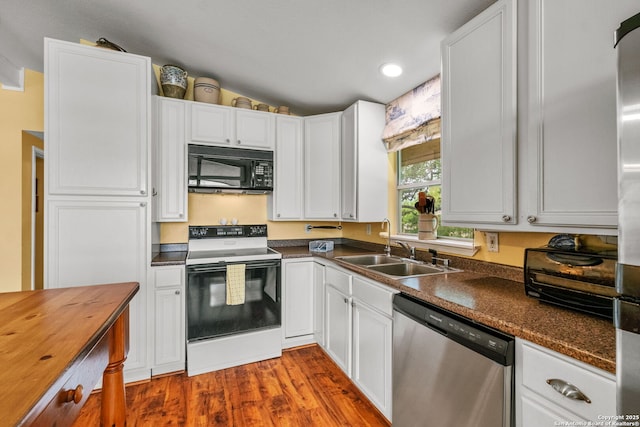 kitchen with stainless steel dishwasher, range with electric stovetop, a sink, black microwave, and lofted ceiling