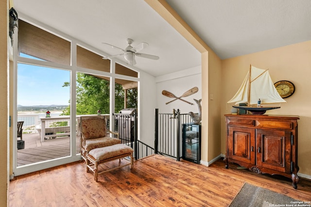 living area featuring lofted ceiling, wood finished floors, ceiling fan, and baseboards