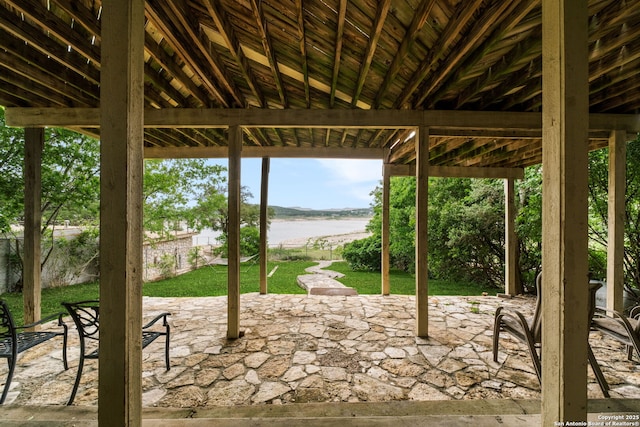 view of patio featuring fence and a water view