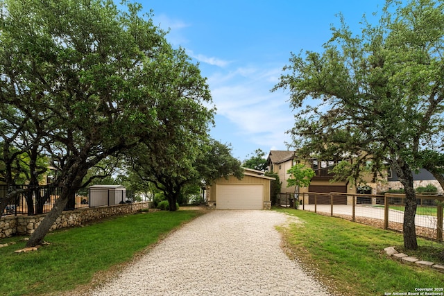 obstructed view of property featuring a garage, fence, a front lawn, and an outbuilding