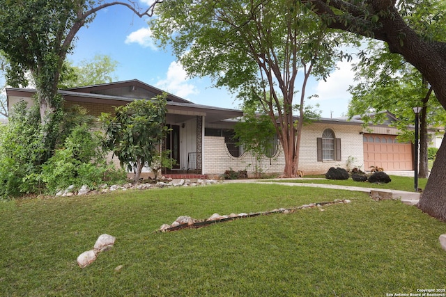 single story home with driveway, a front yard, brick siding, and a garage