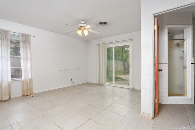 spare room featuring light tile patterned flooring, a ceiling fan, visible vents, and a textured ceiling