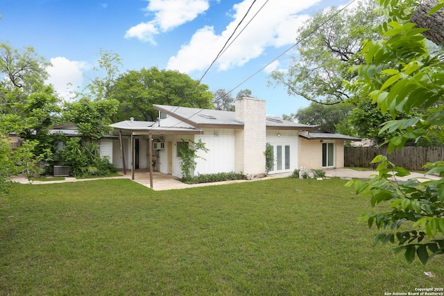 back of house featuring a patio, fence, a chimney, and a lawn
