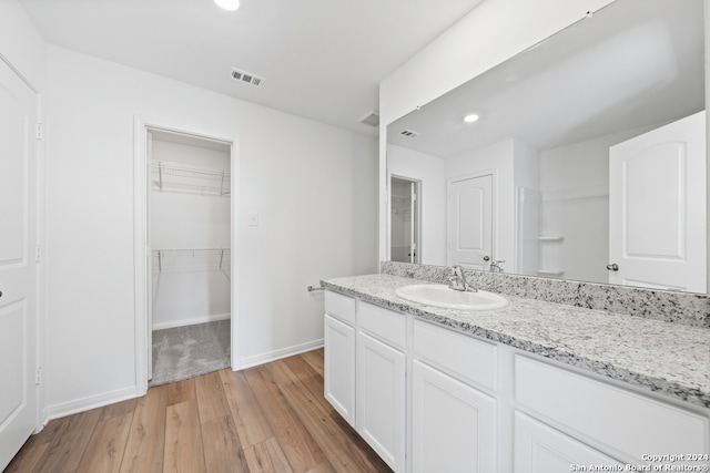 full bathroom featuring recessed lighting, wood finished floors, vanity, baseboards, and visible vents