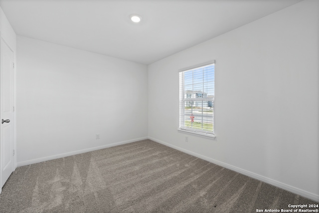 carpeted empty room featuring baseboards