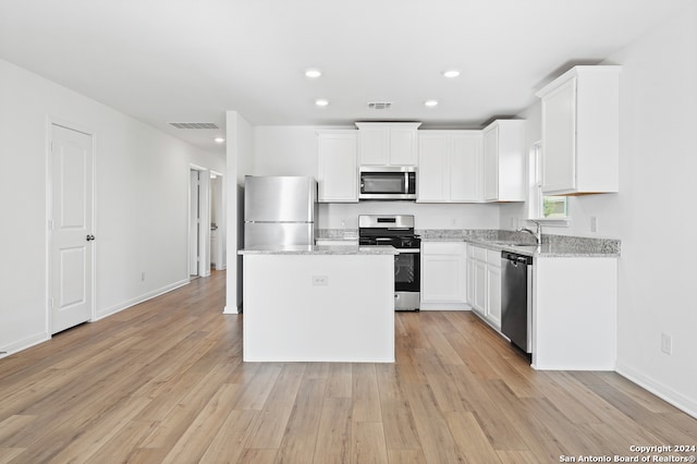 kitchen featuring visible vents, stainless steel appliances, a kitchen island, and white cabinets