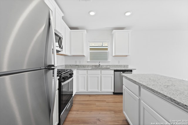 kitchen featuring recessed lighting, a sink, light wood-style flooring, white cabinetry, and appliances with stainless steel finishes