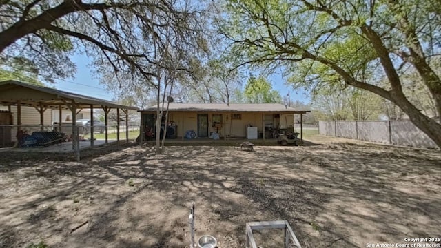 rear view of house with fence and a carport