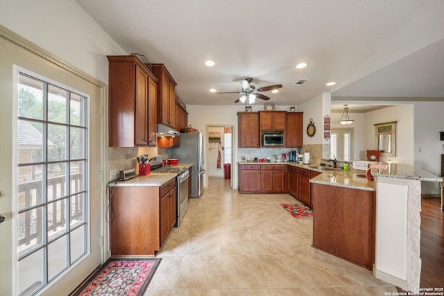 kitchen featuring appliances with stainless steel finishes, tasteful backsplash, under cabinet range hood, and a peninsula