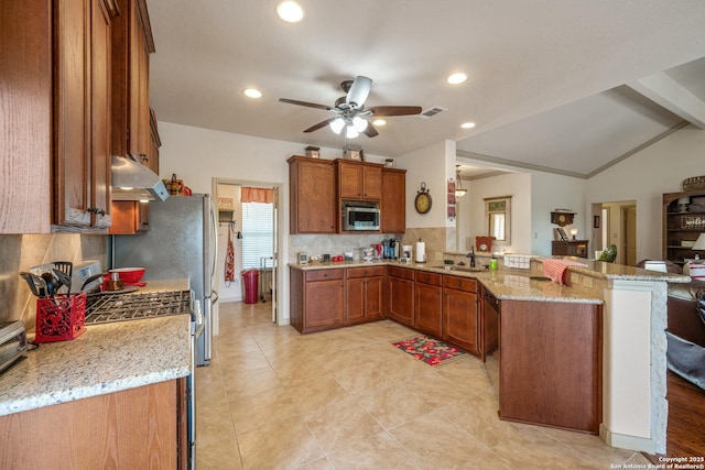 kitchen featuring a peninsula, stainless steel microwave, under cabinet range hood, and brown cabinets