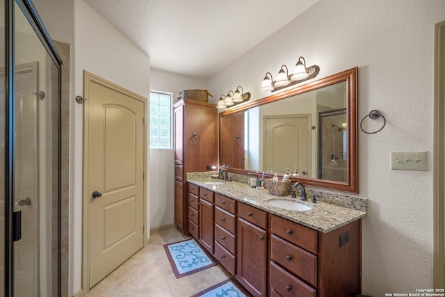 bathroom with a sink, tile patterned floors, a tile shower, and double vanity