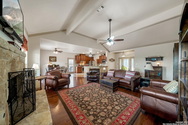 living area featuring a ceiling fan, visible vents, vaulted ceiling with beams, and a fireplace