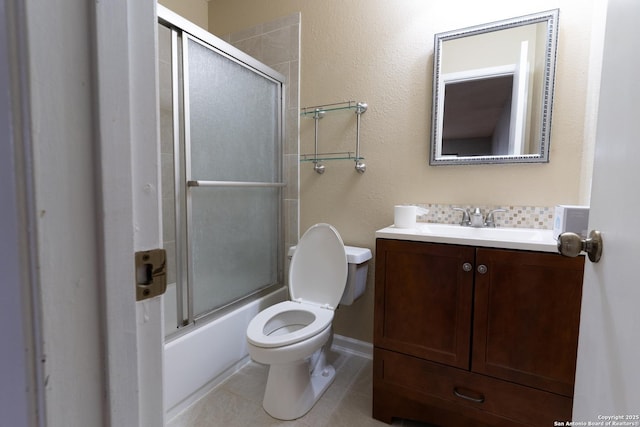 bathroom with combined bath / shower with glass door, vanity, toilet, and tile patterned flooring