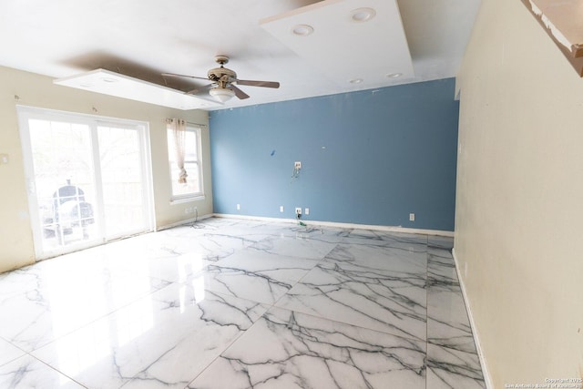 spare room with marble finish floor, ceiling fan, and baseboards