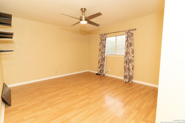 empty room featuring baseboards, a ceiling fan, a textured ceiling, and light wood-style flooring