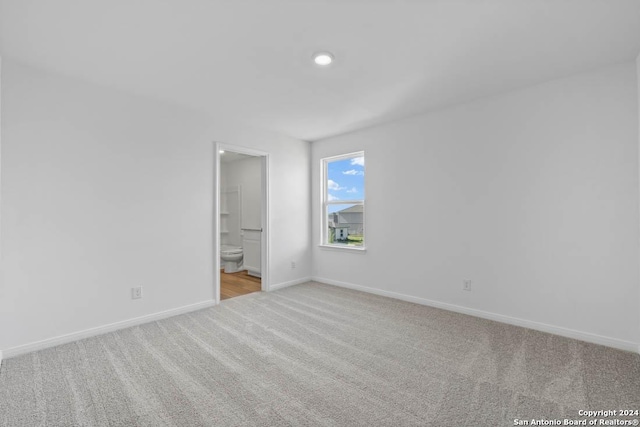 unfurnished bedroom with ensuite bath, recessed lighting, carpet flooring, and baseboards