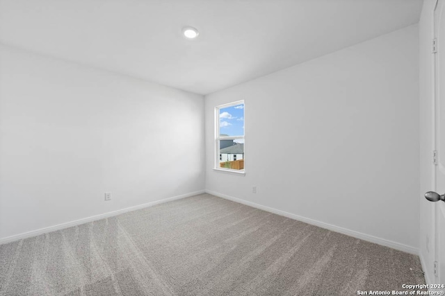 carpeted empty room featuring baseboards