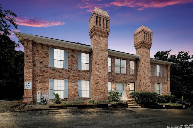 view of front of home with a chimney and brick siding